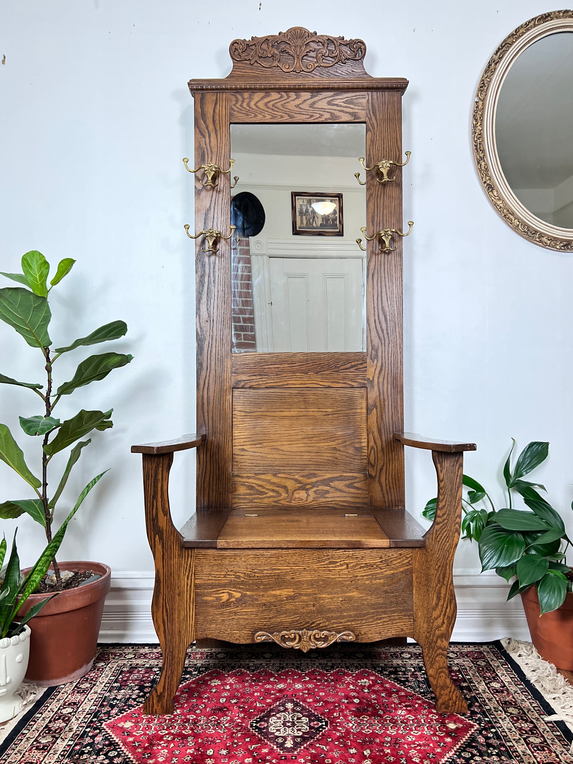 This is an antique oak hall tree bench with mirror, coat hooks & under the seat storage.