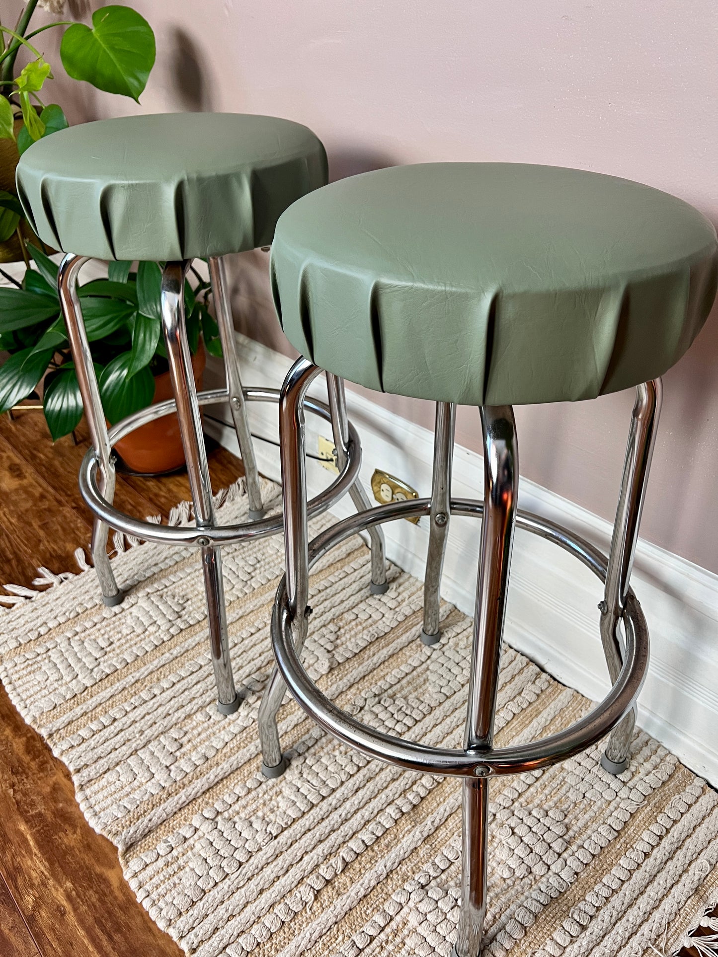 These are vintage bar stools with sage green vinyl tops that swivel and have chrome frames.