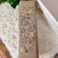 This is a antique beige ottoman footstool with pink and blue floral patterns with birds as well.